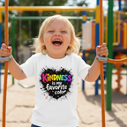 Blonde girl laughing at playground wearing white Kindness t-shirt