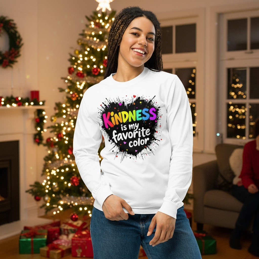 A smiling woman wears a long sleeve tshirt that says "Kindness is my favorite color" in front of a Christmas tree