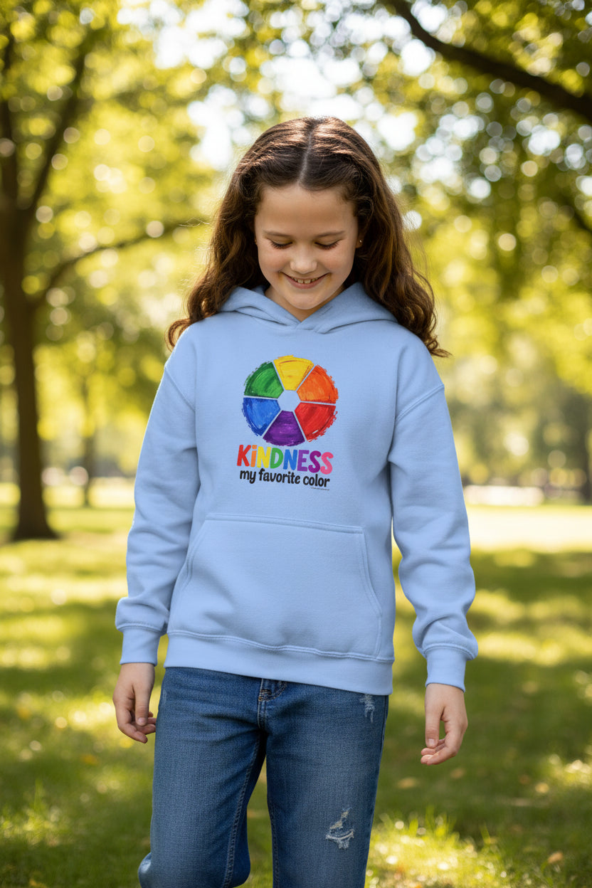 Child in a blue hoodie with the quote "Kindness is my favorite color". She is in a park on a sunny day.